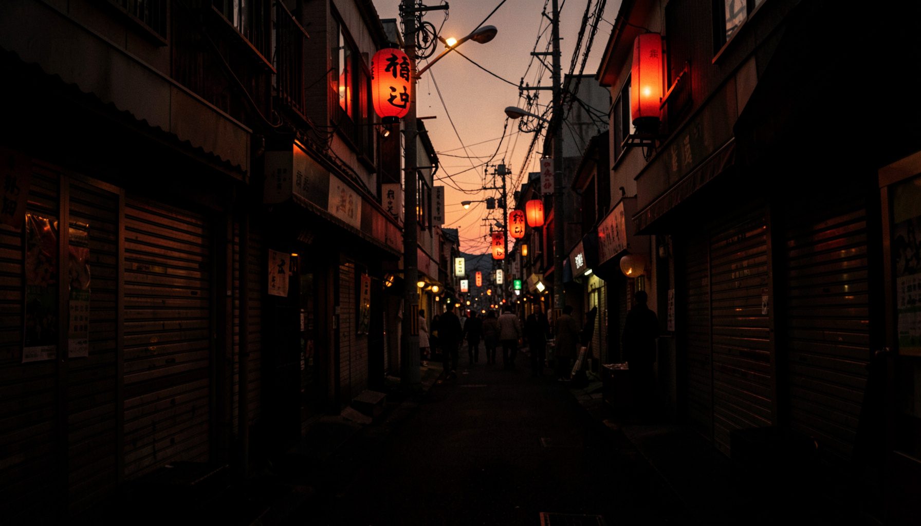 夕暮れの福島県内商店街の風景。赤提灯とシャッター街が柔らかな光に照らされ、暖かいオレンジと深い影が混ざり合う、もの悲しいけれど温かみのある写真