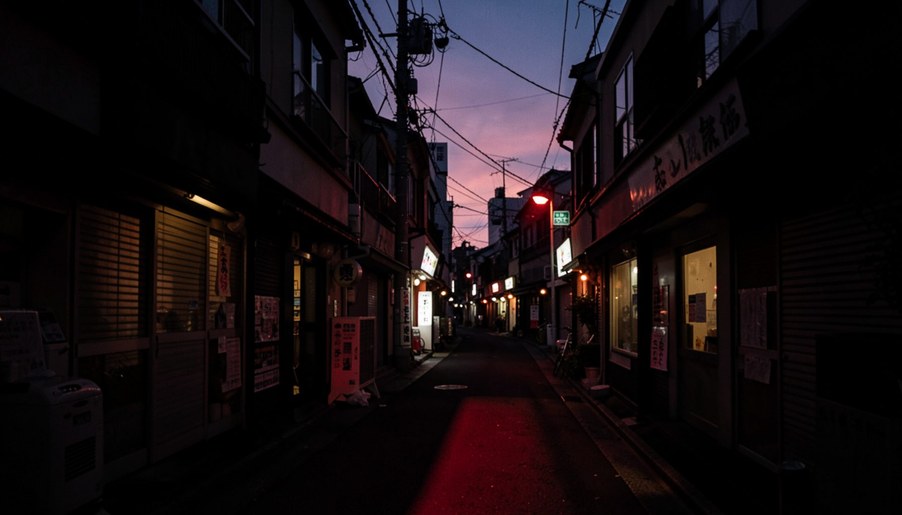 福島の商店街の夕暮れ、シャッターの下りた店舗が並ぶ静かな通り、深い影と暖かみのある街灯の光