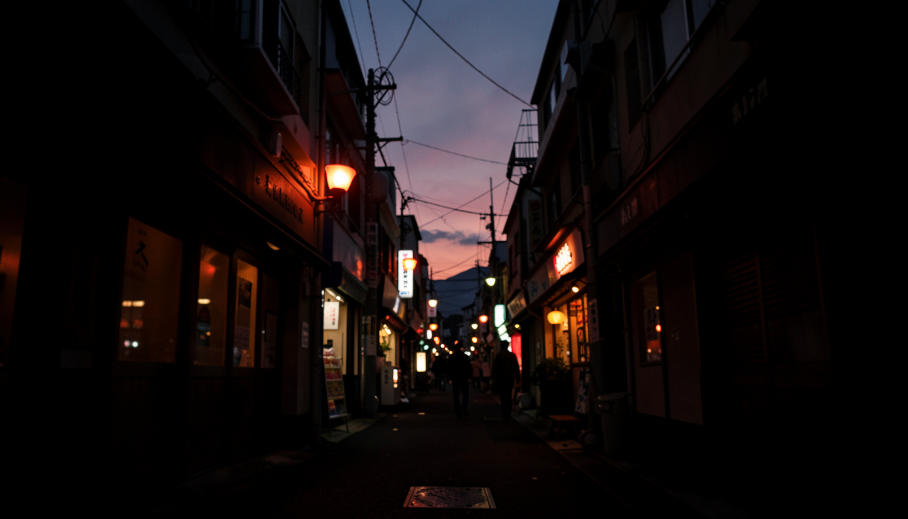 福島の商店街の夕暮れ、温かみのある街灯が並ぶアーケード通りを低い視点から捉えた暗めの写真